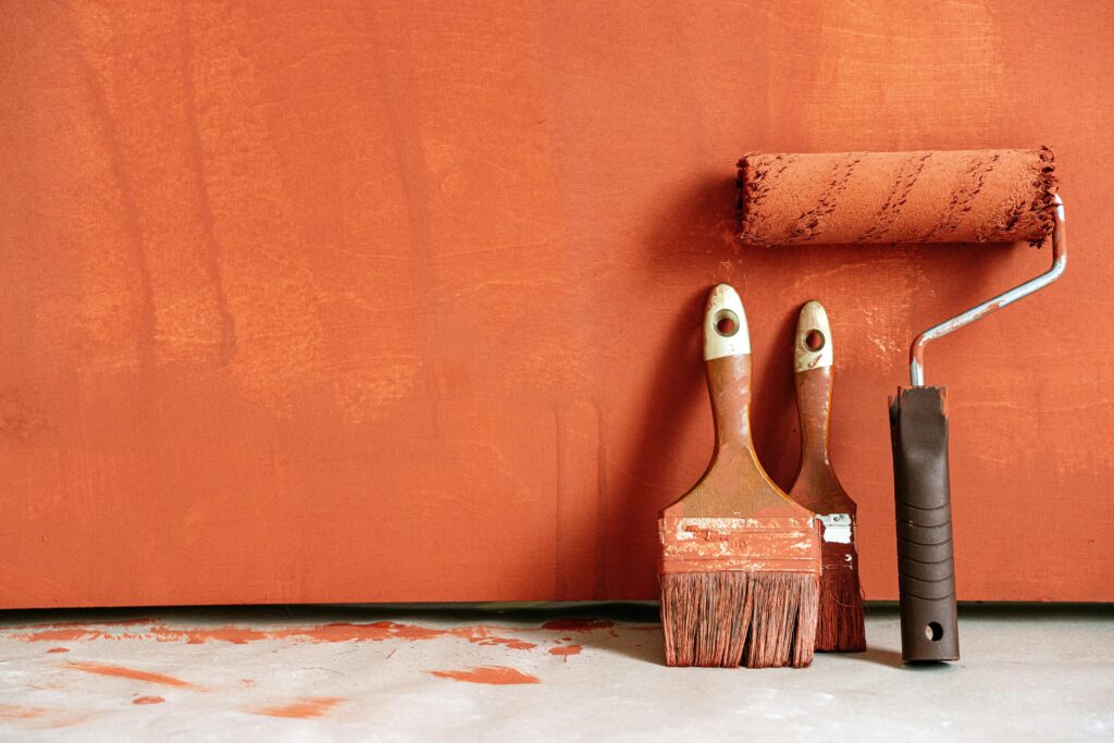 paint brushes laying against a painted wall