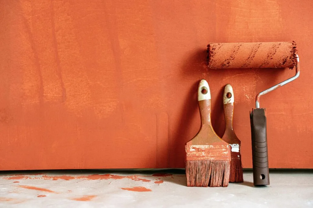 paint brushes laying against a painted wall